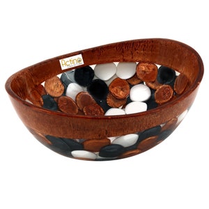 May include: A wooden bowl with a clear resin insert filled with white, black, and brown stones. The bowl is oval shaped and has a brown wood finish. The text "Actino Design & Style" is visible on the bowl.
