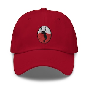 May include: A red baseball cap with an embroidered white and red circle featuring a silhouette of a person playing tennis.