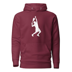 Puede incluir: Sudadera con capucha burdeos con una silueta blanca de un tenista sacando. La sudadera tiene una capucha con cordón y un bolsillo delantero. Prenda deportiva para los entusiastas del tenis.