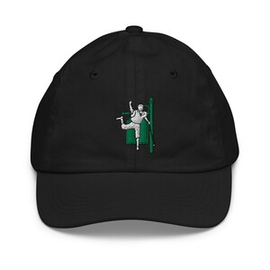 Op de afbeelding: Zwarte baseballcap met een gebogen klep. De cap heeft een geborduurd ontwerp van een persoon in een witte outfit, met een groene achtergrond en een groene paal. Het ontwerp staat op de voorkant van de cap.