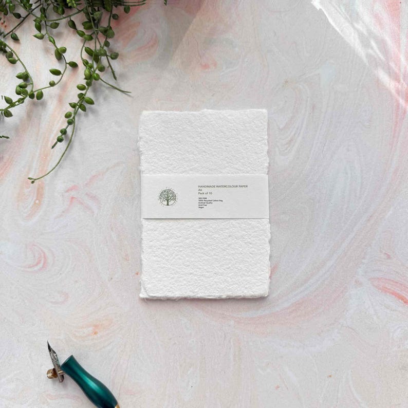 White textured notebook with a pen on a light pink background