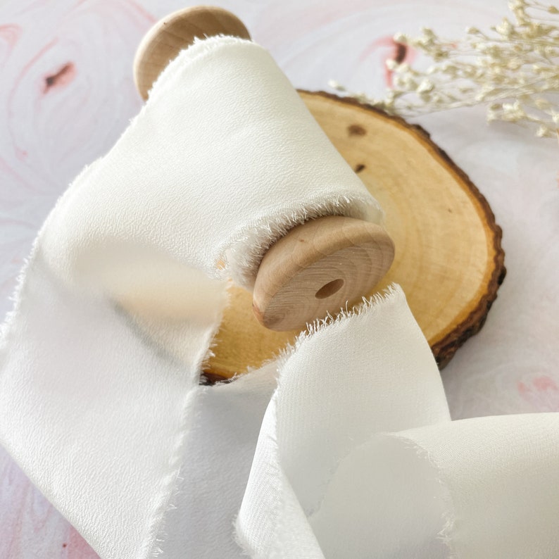 White habotai silk ribbon on a wooden spool.  Wide silk ribbon with a raw edge.