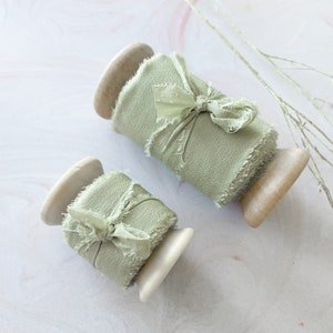sage green habotai silk ribbon with raw edge.  Raw edge silk ribbon on a wooden reel.