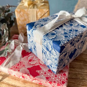 Gift boxes wrapped in blue and red patterned paper with white ribbons on a wooden surface.
