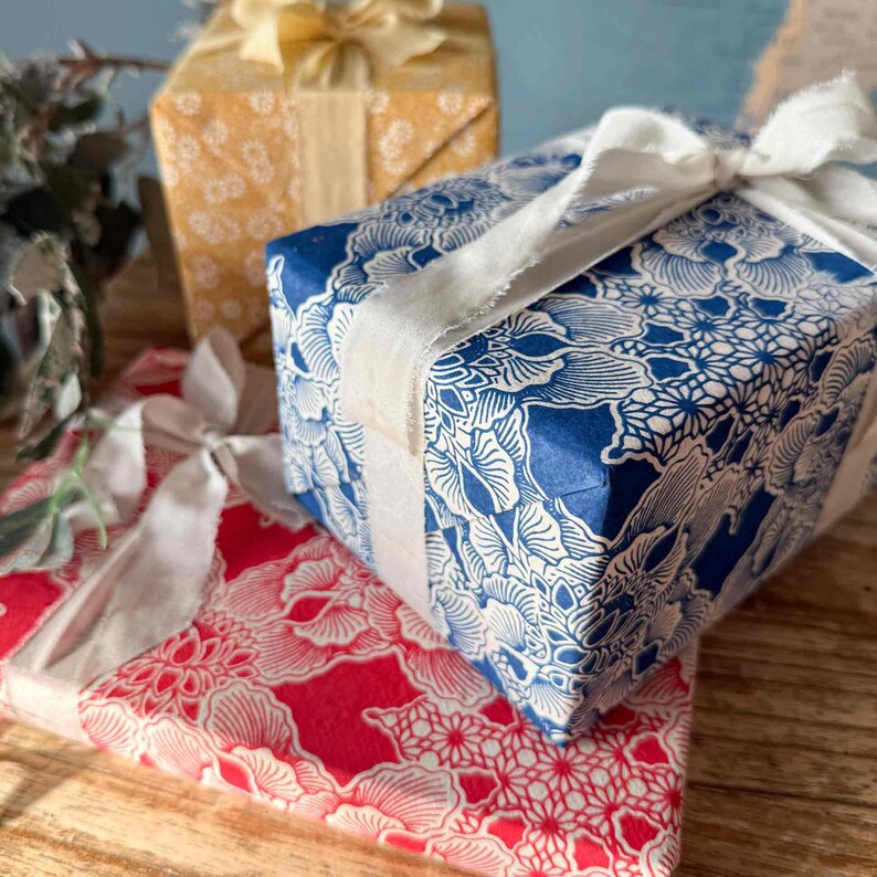 Gift boxes wrapped in blue and red patterned paper with white ribbons on a wooden surface.