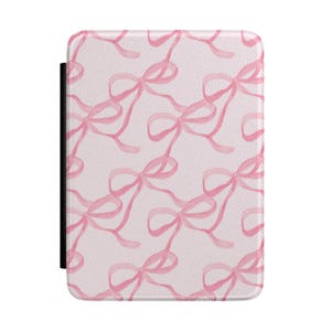 Könnte beinhalten: Eine rechteckige Hülle mit hellrosa Hintergrund und einem sich wiederholenden Muster aus rosa Aquarellschleifen. Die Hülle hat eine schwarze Wirbelsäule auf der linken Seite. Die Schleifen sind in verschiedenen Größen und Ausrichtungen.