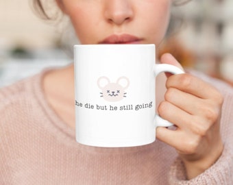 May include: White ceramic coffee mug with a cartoon mouse illustration and the text "he die but he still going".