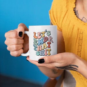 May include: White ceramic mug with a colorful graphic that says "Let's EMDR That Shit".