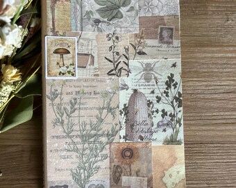 May include: A brown notebook with a collage of vintage botanical illustrations, including mushrooms, flowers, and insects. The notebook has a textured paper cover and a simple design.