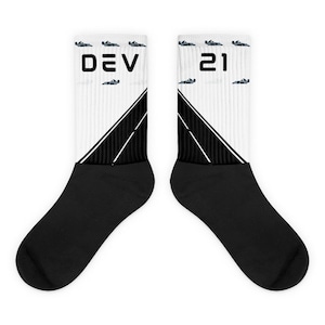 May include: A pair of white and black socks with a racing track design. One sock has the text "DEV" and the other has the number "21".