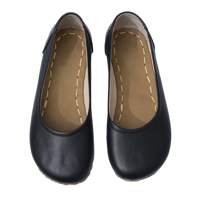 May include: A pair of black leather ballet flats with a rounded toe and a simple design.