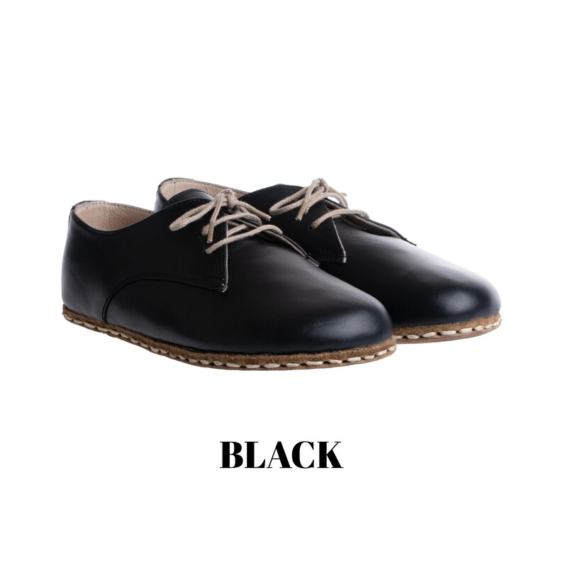 May include: A pair of black lace-up shoes with a rounded toe, light beige laces, and a visible tan stitched welt along the sole. The word BLACK is printed in bold, black, sans-serif capital letters centred below the footwear.