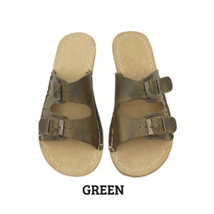 May include: A pair of green leather sandals with two adjustable buckle straps. The sandals have a light brown footbed and white stitching around the edges. The word "GREEN" is printed in black at the bottom.