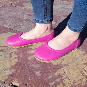 May include: A pair of bright pink ballet flats with a woven sole. The flats are made of leather and have a simple, elegant design.