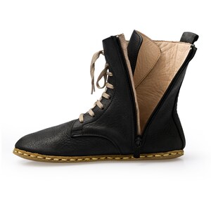 May include: Black leather ankle boots with a zipper up the back and laces. The boots have a brown stitched sole.
