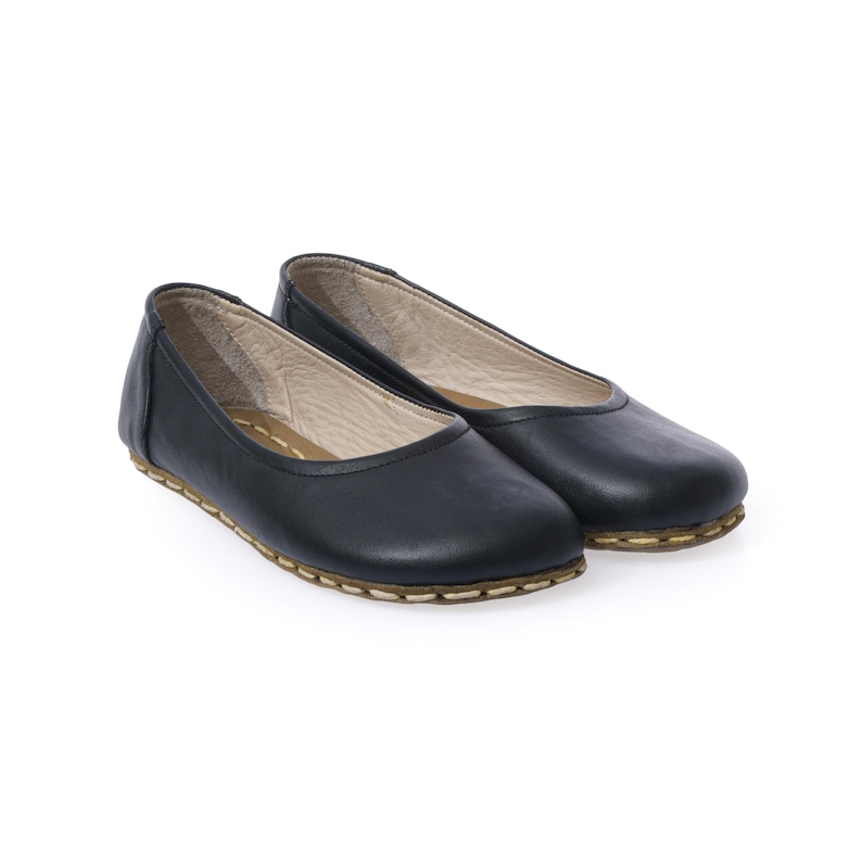 May include: A pair of black leather ballet flats with a brown stitched edge.