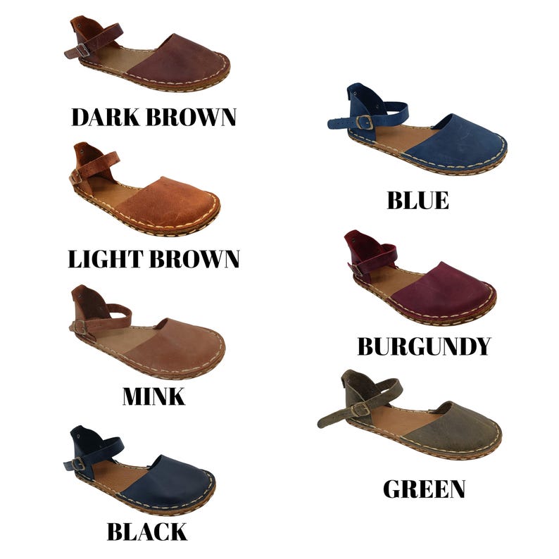 May include: A collection of seven flat sandals in dark brown, light brown, mink, black, blue, burgundy, and green. Each sandal features a rounded toe, a single ankle strap with a metal buckle, and visible white stitching along the sole edge.