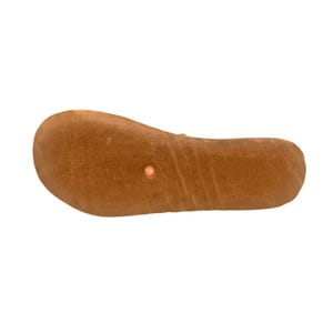 May include: A brown leather shoe sole with a textured surface. The sole has a rounded toe and a small, circular, reddish-orange emblem near the center. The overall shape is elongated and curved.