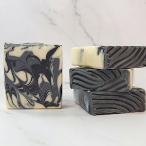 May include: Two bars of soap, one with a black and white marbled design and the other with a black and white striped design.