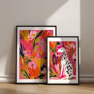 May include: Two framed art prints with black borders. The larger print features a vibrant floral pattern in shades of pink, orange, and yellow. The smaller print depicts a white dog with black spots sitting amidst a colorful garden of flowers.