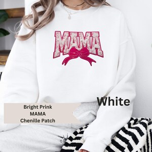 May include: White sweatshirt with the word "MAMA" in bright pink chenille patch letters, with a matching pink bow. The sweatshirt also has the words "Bright Pink" and "Chenille Patch" printed on it.