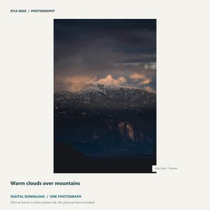 May include: A digital photograph titled Warm clouds over mountains by Kyle Seko Photography. The image displays a dark, rugged mountain range with snow-capped peaks partially obscured by heavy, dark clouds illuminated by warm, golden light at sunset.
