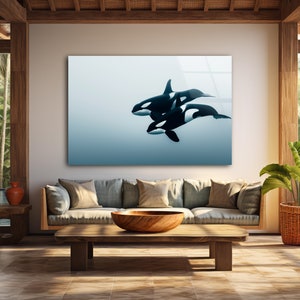 Puede incluir: Una impresi&oacute;n enmarcada de tres orcas blancas y negras nadando en un oc&eacute;ano azul. La impresi&oacute;n est&aacute; colgada en una pared de una sala de estar con un sof&aacute;, una mesa de caf&eacute; y una planta en maceta.