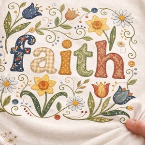 May include: Cream-coloured fabric featuring the word "Faith" embroidered in colourful, patchwork-style letters. The letters are surrounded by a floral design with daisies, daffodils, and tulips in various colours, with small buttons and delicate vines.