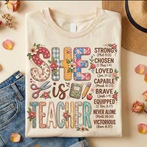 Op de afbeelding: Crèmekleurig T-shirt met de woorden "SHE is TEACHER" in kleurrijke letters in patchwork-stijl. Het shirt bevat inspirerende woorden als "STRONG" en "BRAVE" met bijbelverzen. Schaar, notitieboek en potlood zijn ook afgebeeld.
