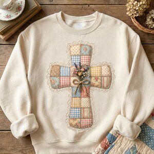 Puede incluir: Sudadera de color crema con un dise&ntilde;o de cruz de patchwork. La cruz est&aacute; adornada con patrones florales y de cuadros, un ribete de encaje y un ramo de flores secas atado con un lazo. Una prenda superior c&oacute;moda y elegante.