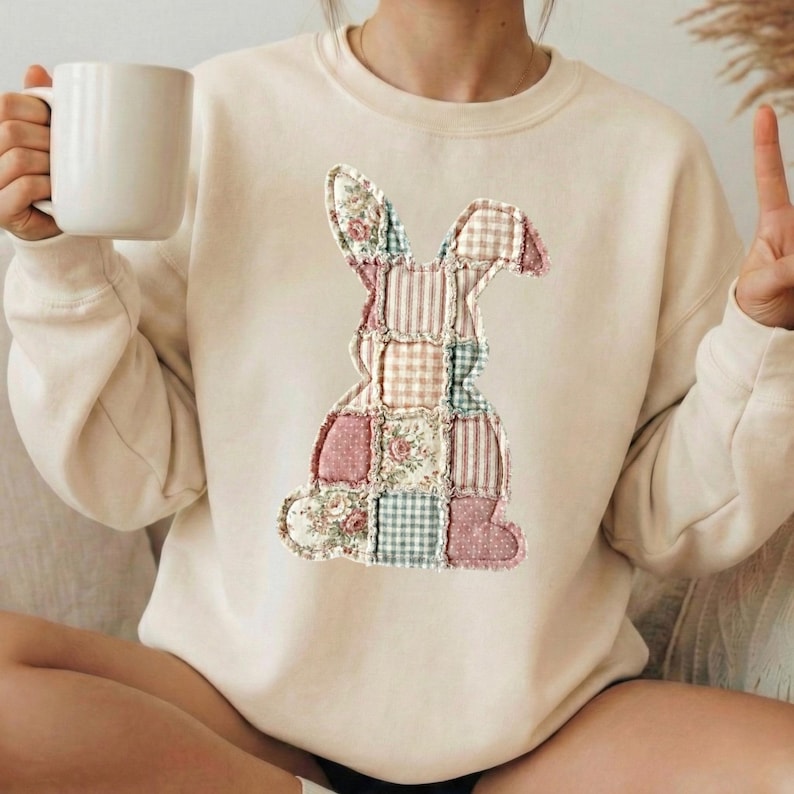 Puede incluir: Sudadera de color crema con un dise&ntilde;o de conejo de patchwork. El conejo est&aacute; compuesto por varios patrones de tela, incluyendo estampados florales, a rayas y a cuadros en colores pastel. La sudadera tiene mangas largas y cuello redondo.