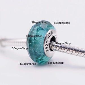 Puede incluir: Una cuenta facetada de color turquesa con un núcleo de metal plateado y una cadena de serpiente. La cuenta tiene un interior brillante y moteado. El núcleo de metal está estampado con "S925 ALE". La cuenta es de SBegumShop.