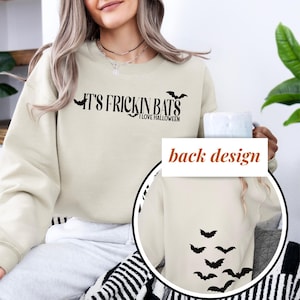 May include: A beige sweatshirt with the text "It's Frickin Bats I Love Halloween" on the front and a design of bats on the back.