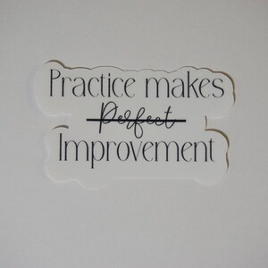 May include: White sticker with black text that reads "Practice makes perfect" with a line through the word "perfect" and the word "improvement" below it.