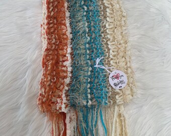 May include: Handmade scarf with a textured design. The scarf features vertical stripes in shades of orange, cream, and teal. The scarf has a fringed edge and a tag that says "Thank you, Sidahda Shop".