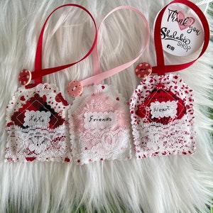 May include: Three handmade fabric ornaments with lace trim and ribbon hangers. One has "Xoxo" on it, another says "Friends", and the third says "Heart". Each has a button and a tag that says "Thank you Shalakee Shop".