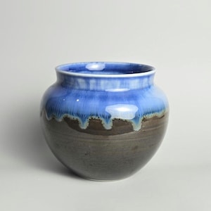 May include: A ceramic vase with a blue and brown glaze. The glaze has a drip effect, creating a unique and artistic look.