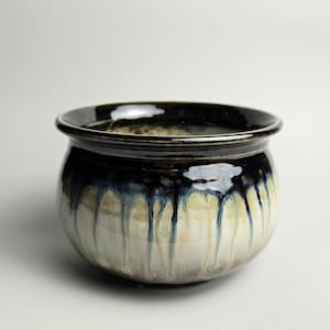 Peut inclure: Un bol en céramique rond doté d'une finition brillante avec un bord bleu marine foncé qui se transforme en une base de couleur crème. L'émail présente un motif de gouttes distinct où la couleur bleue foncée coule verticalement.