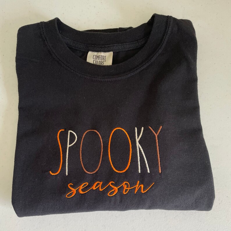 May include: Black sweatshirt with the text "SPOOKY season" embroidered in orange and white.