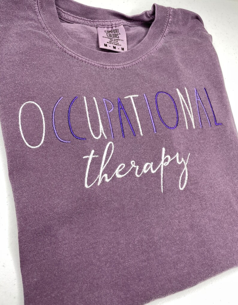 May include: Purple t-shirt with the text "OCCUPATIONAL therapy" embroidered in white.