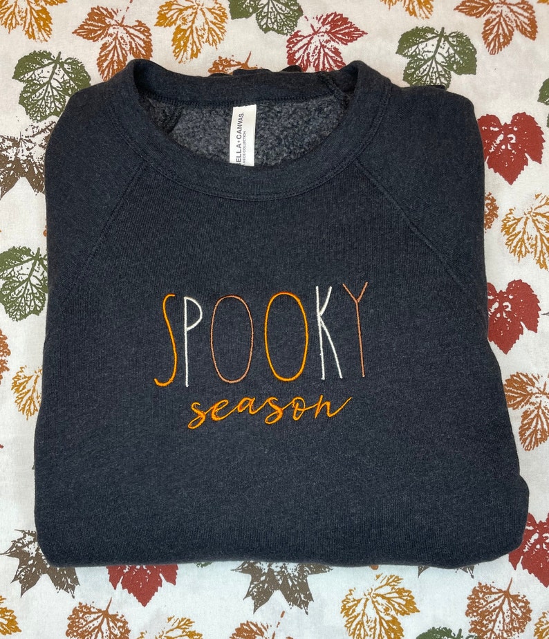 May include: Black sweatshirt with the text "SPOOKY season" embroidered in orange and white thread.