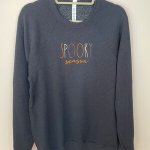 May include: A dark gray sweatshirt with the text "SPOOKY season" in orange and white lettering.
