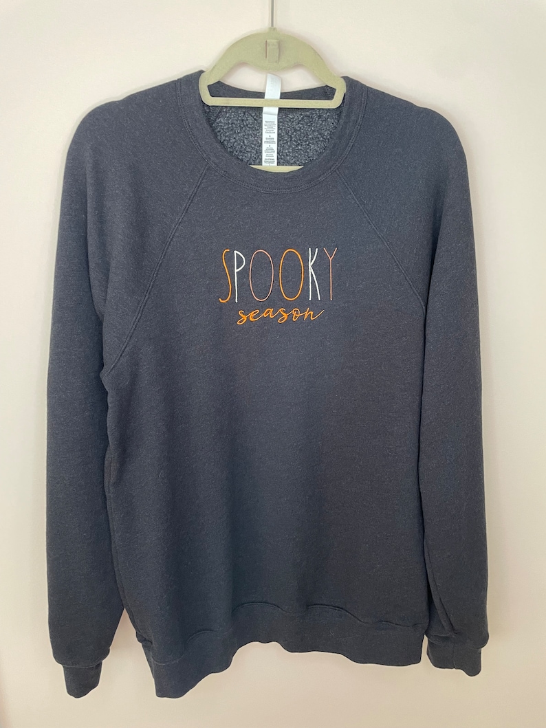 May include: A dark gray sweatshirt with the text "SPOOKY season" in orange and white lettering.