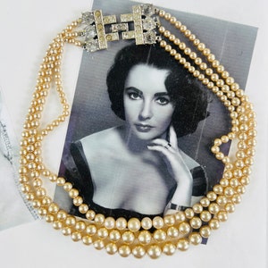 May include: A multi-strand pearl necklace with a silver and rhinestone clasp. The necklace is laying on a black and white photo of a woman.