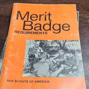 May include: An orange booklet titled "Merit Badge Requirements" with a black and white photo of Boy Scouts in a wooded area. The booklet is published by Boy Scouts of America.
