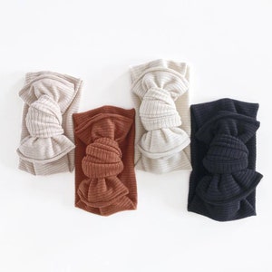 May include: Four fabric headbands with knotted bows in beige, brown, black, and white.