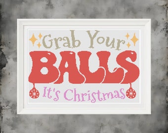 Może przedstawiać: Haftowany krzyżykiem obraz w białej ramie z tekstem "Grab Your Balls It's Christmas" w retro czcionce. Słowo "Balls" jest czerwone, a reszta tekstu jest beżowa i różowa.