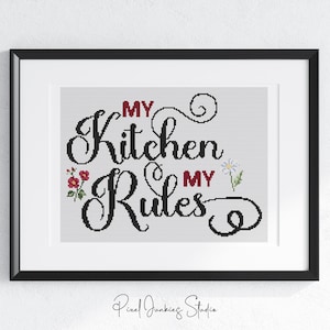 May include: Framed artwork with the text "My Kitchen My Rules" in a black script font. The words "My" are in red. Small floral accents are on either side of the text. The artwork is in a white mat and black frame.