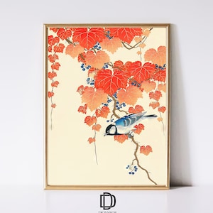 Puede incluir: Una impresión japonesa vintage en madera que representa un pájaro azul y blanco posado en una rama con hojas rojas y naranjas y bayas azul oscuro. La impresión está enmarcada en un marco dorado.