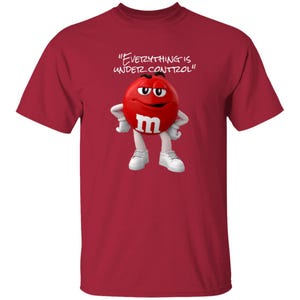 May include: Red t-shirt featuring a cartoon red M&M character with the text "EVERYTHING IS UNDER CONTROL". The character has white gloves, shoes, and the letter "m" on its front.